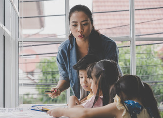 Asian Teacher is teaching children in kindergarten classroom