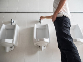 Man standing press flushing a urinal in a public washroom