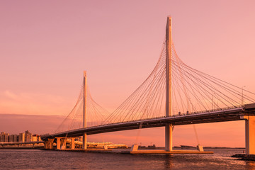 The bridge of circle highway road over Neva river near the mouth of it in the blue hour during the sunset. Evening view on the buildings of Petersburg city and the Finish gulf