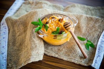 boiled sweet pumpkin porridge with raisins and nuts in a glass bowl