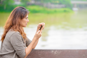 Middle age asian women using a smart phone for friend connection. Up country women using a cell phone checking e-mail or an application outdoor.