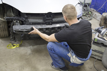 Fototapeta na wymiar professional repairman worker in automotive industry sanding plastic body car bumper