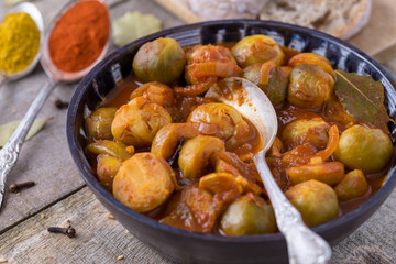 Roasted brussels sprouts soup in homemade ceramic bowl on natural wooden background.