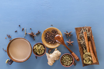 Traditional Indian tea masala with milk and spices on a blue background. Top view. Copy space