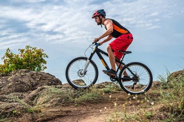 Obraz premium Cyclist in a helmet and with a backpack riding down the rock on a mountain bike, an active lifestyle.