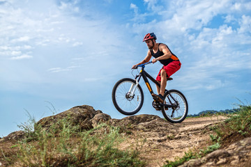 Fototapeta na wymiar Concept of extreme cycling, a biker on a mountain bike on the blue sky background, free space.