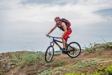 Fototapeta na wymiar Cyclist on a mountain bike riding on the rock, free space for your text.