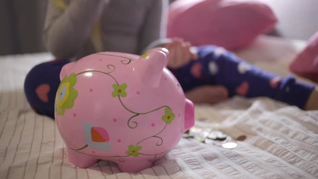 Close up footage of a five year old girl checking her piggy bank and saving money