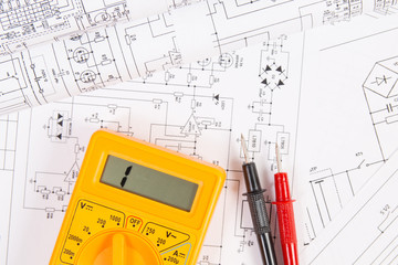 Electrical engineering drawings and digital multimeter.