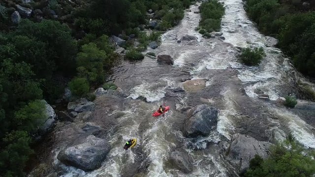 Aerial footage of white water kayaks paddling in the white water rapids on a freestone stream in the western cape of south africa during a winter storm.