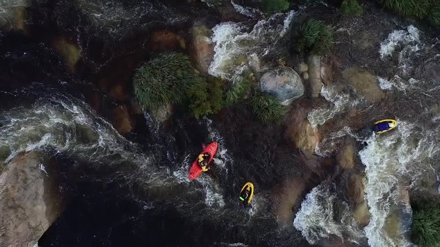 Aerial footage of white water kayaks paddling in the white water rapids on a freestone stream in the western cape of south africa during a winter storm.