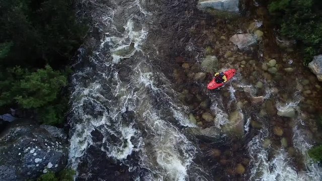 Aerial footage of white water kayaks paddling in the white water rapids on a freestone stream in the western cape of south africa during a winter storm.