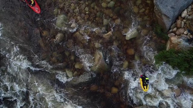 Aerial footage of white water kayaks paddling in the white water rapids on a freestone stream in the western cape of south africa during a winter storm.