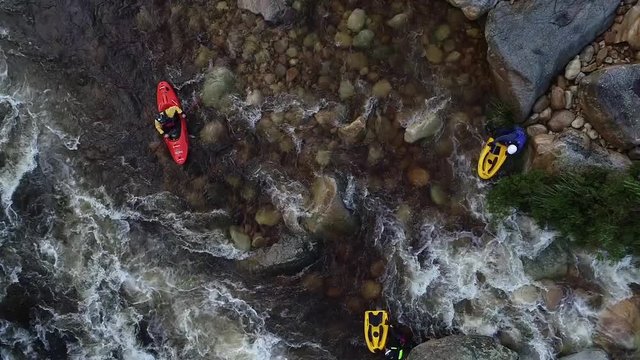 Aerial footage of white water kayaks paddling in the white water rapids on a freestone stream in the western cape of south africa during a winter storm.