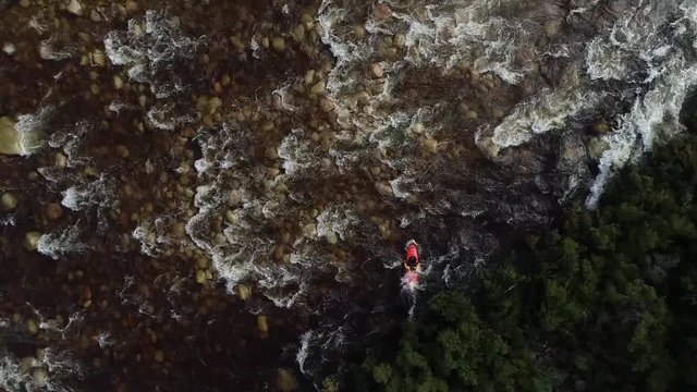 Aerial footage of white water kayaks paddling in the white water rapids on a freestone stream in the western cape of south africa during a winter storm.