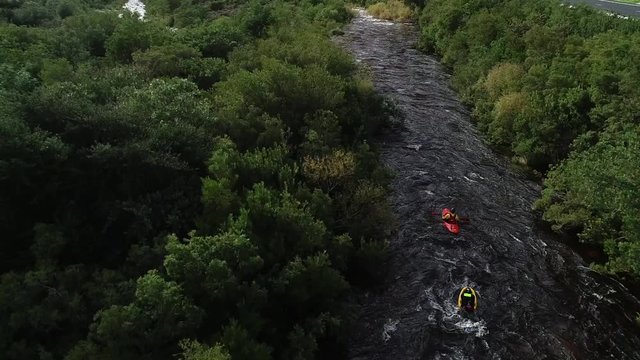Aerial footage of white water kayaks paddling in the white water rapids on a freestone stream in the western cape of south africa during a winter storm.