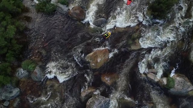 Aerial footage of white water kayaks paddling in the white water rapids on a freestone stream in the western cape of south africa during a winter storm.