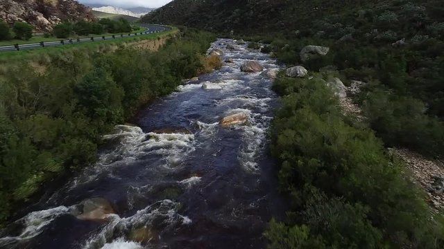 Aerial footage of white water kayaks paddling in the white water rapids on a freestone stream in the western cape of south africa during a winter storm.