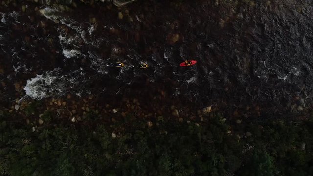 Aerial footage of white water kayaks paddling in the white water rapids on a freestone stream in the western cape of south africa during a winter storm.
