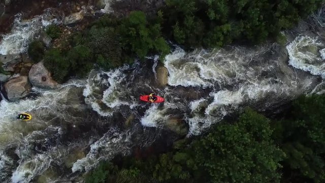 Aerial footage of white water kayaks paddling in the white water rapids on a freestone stream in the western cape of south africa during a winter storm.