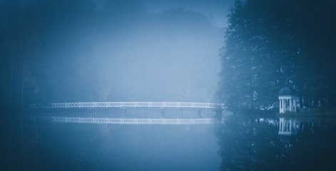 Long white foot bridge over a lake shot in morning mist