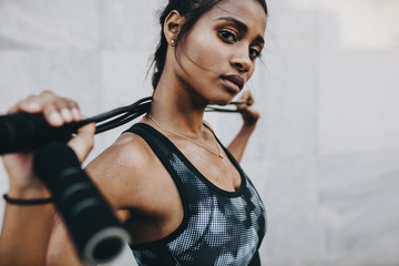 Portrait of a fitness woman standing with a skipping rope on her - obrazy, fototapety, plakaty