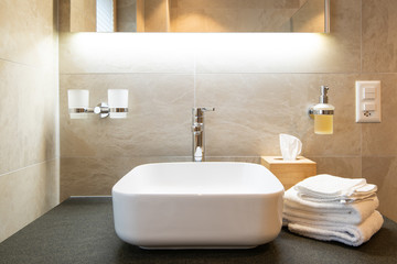 Close-up view of bathroom sink , shelf, towels and soap dispenser