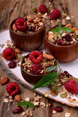 Granola decorated with raspberries in wooden bowls on the table