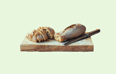 Baguette cut into slices on a wooden chopping board with a bread knife