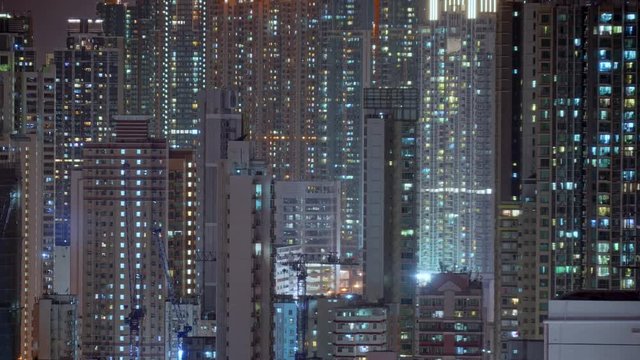 Wide day to night transition timelapse of Hong Kong apartments. Chinese crowded city with lights turning on and off at midnight. Fast paced modern Asian night-scape time lapse in urban metropolis.