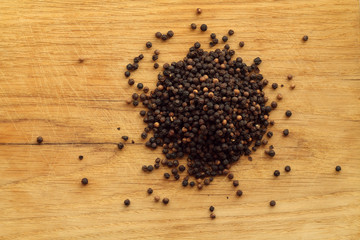 Black pepper close-up on wooden desk.
