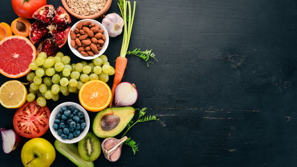 Healthy food clean eating selection: Vegetables, fruits, nuts, berries and mushrooms, parsley, spices. On a black background. Free space for text.