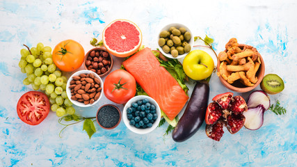 A set of healthy food. Fish, nuts, protein, berries, vegetables and fruits. On a white background. Top view. Free space for text.