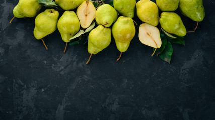 Fresh pears on a black stone table. Fruits. Free space for text. Top view.