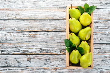 Assortment of pears in a wooden box. On a white wooden table. Free space for text. Top view.