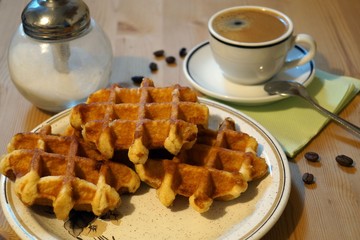 Belgian waffles, a cup of coffee and a glass sugar dispenser