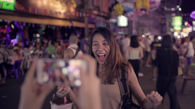 Traveler backpacker blogger Asian women lesbian lgbt couple travel using smartphone takes photos in Thailand. Female drinking alcohol or beer at Khao San Road the most famous street in Bangkok.