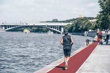 An athletic man is hanging out in sports, warming up and performing running exercises for his health on a treadmill city street cycle track