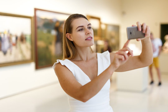 Woman photographing painting in museum