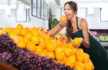 Obraz premium Positive woman seller holding orange in hand