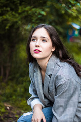 Model in a gray jacket sitting on a stump