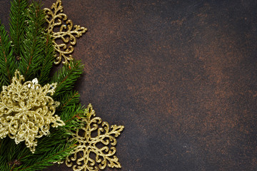 Christmas tree and decorative snowflakes, bells, ribbons on a brown background with space under the text.