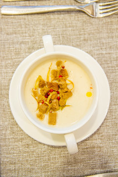 Cream soup decorated with croutons , onion and red pepper