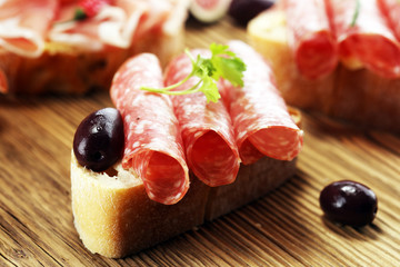 Sandwich with prosciutto or salami or crudo. Antipasti gourmet bruschetta snack.