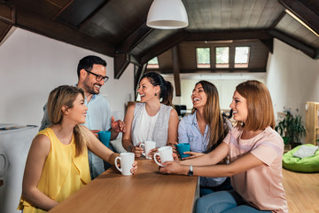 Five coworkers laughing while on the break in modern coworking space.