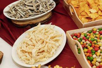 salty smoked squid and anchovies on wooden desk on table, wedding reception. beer bar and snacks. catering in restaurant