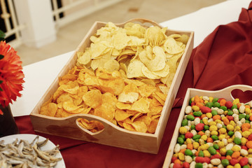 salty chips and nuts on wooden desk on table, wedding reception. beer bar and snacks. catering in restaurant