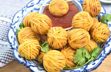 Deep Fried Wrapped Pork with Noodle Thai traditional snacks menu ( Thai name is Moo sarong) in Thai style bowl with cucumber salad and sweet chili sauce.