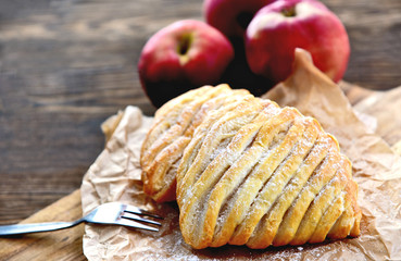 Easy Apple Turnovers (German name is Apfeltaschen) on brown paper with fresh red apples on wooden...
