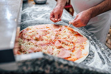Close-up image of chef making the pizza.